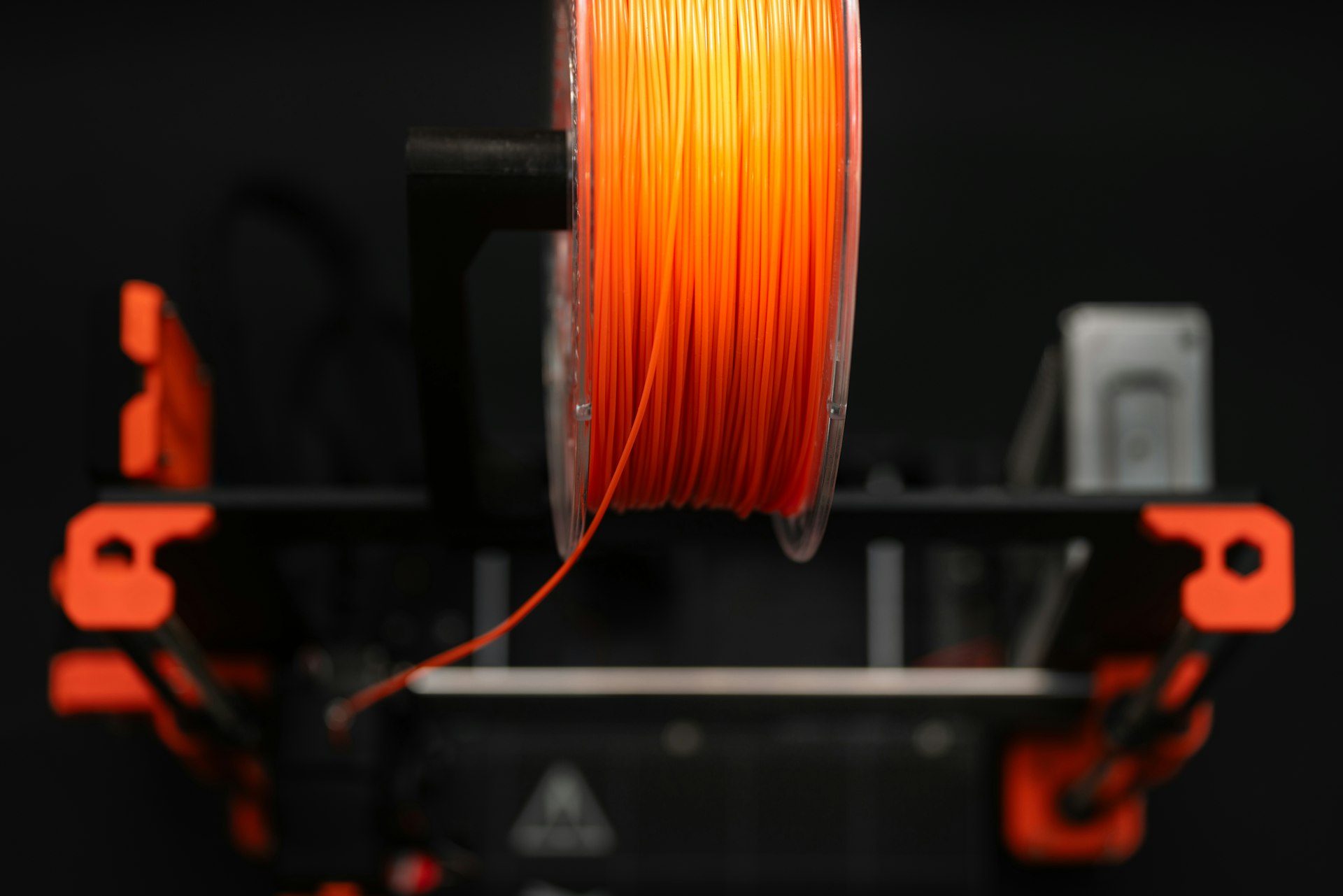 A spool of orange colored pla on a machine